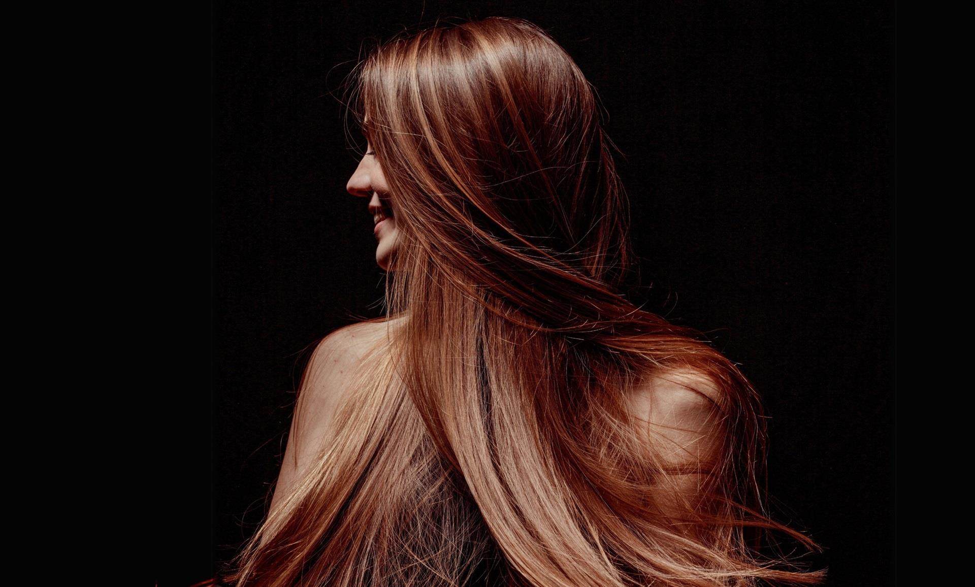 Photo of a white woman with long brown hair looking to the left. The hair obscures much of her face.