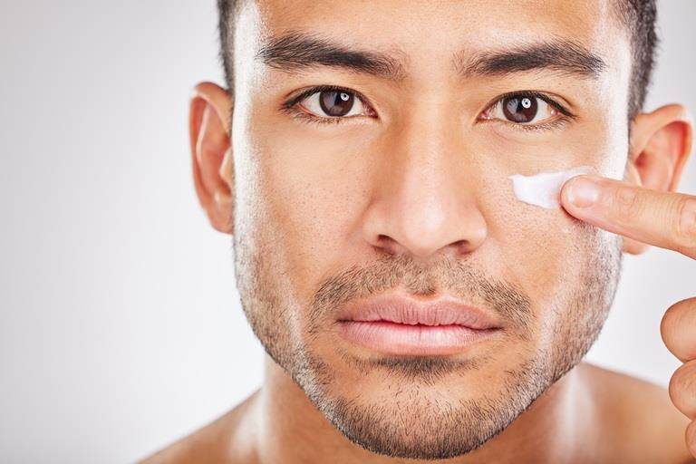 East asian man applying cream to face
